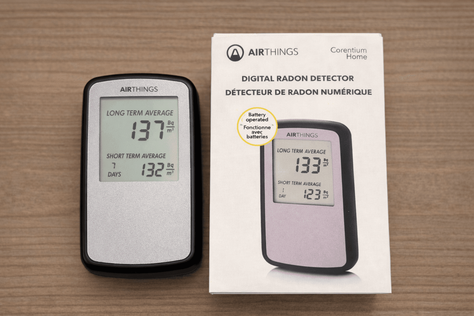 Digital radon detector and packaging on a wooden surface.